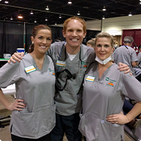 Doctor Altenbach and two dental team members in matching in gray shirts at event