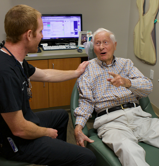 Doctor Altenbach placing his hand on shoulder of senior man in dental chair