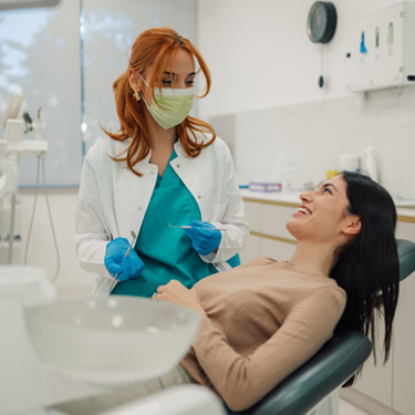 Patient in treatment chair smiling at dentist