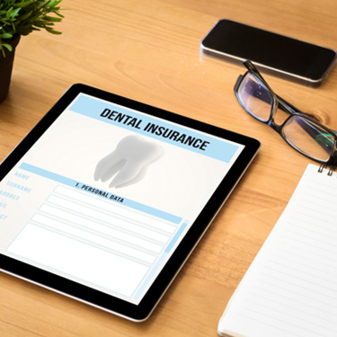 Dental insurance form on tablet next to office supplies