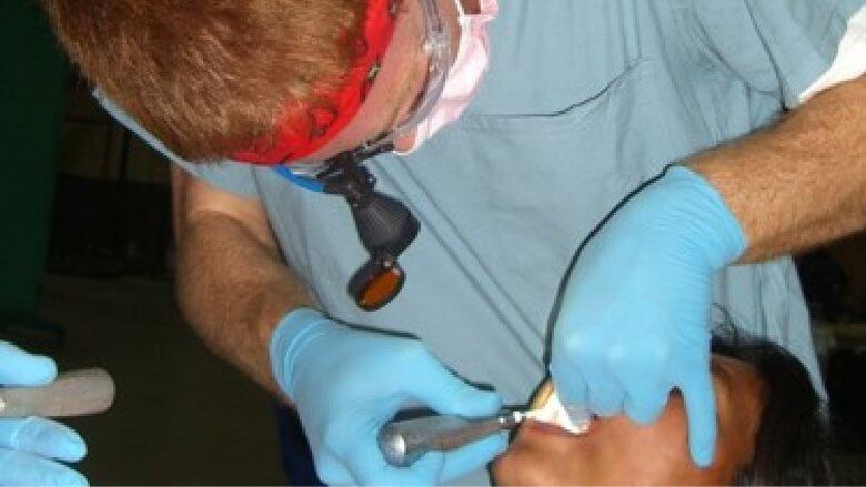 Doctor Altenbach shining flashlight into a child's mouth during dental exam