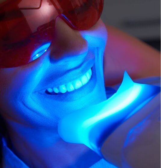 Woman receiving professional teeth whitening in dental office