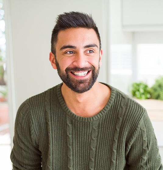 Smiling bearded man sitting in his kitchen