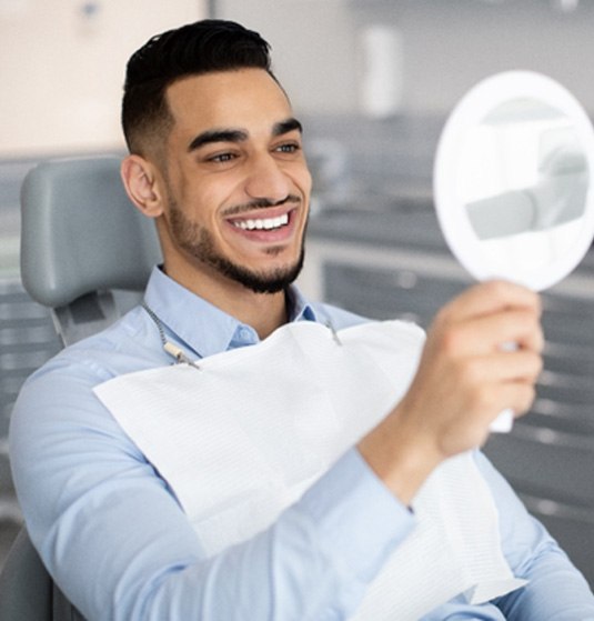 Male dental patient checking smile in mirror