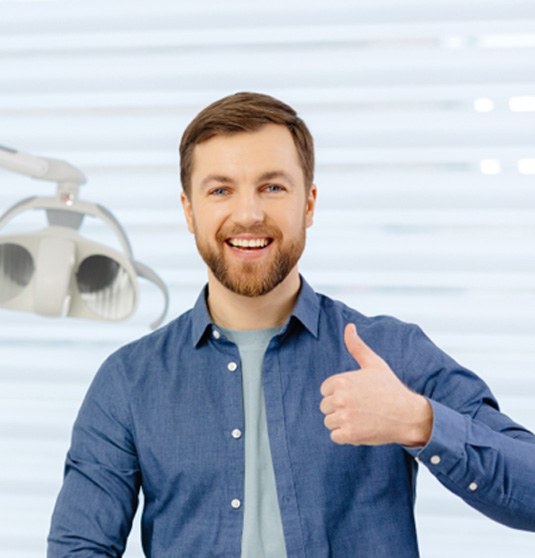 Man in dentist’s office giving a thumb’s up