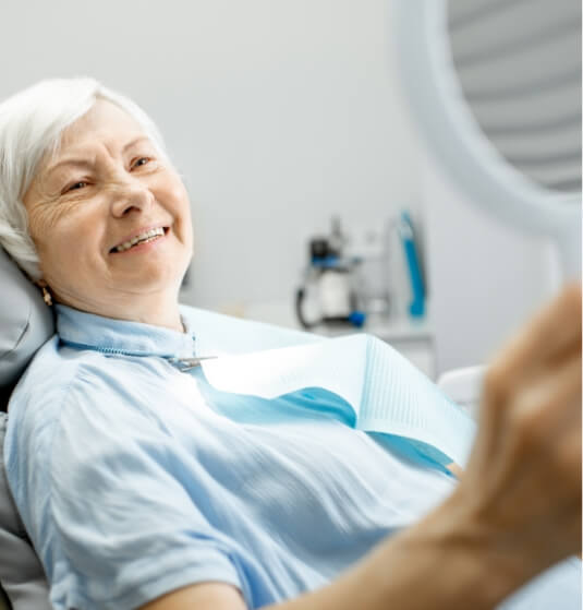 Senior dental patient looking her her smile in mirror