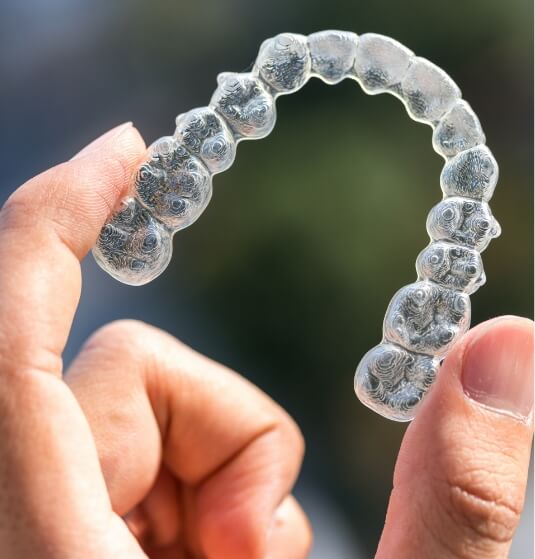 Person holding an Invisalign aligner in Jacksonville