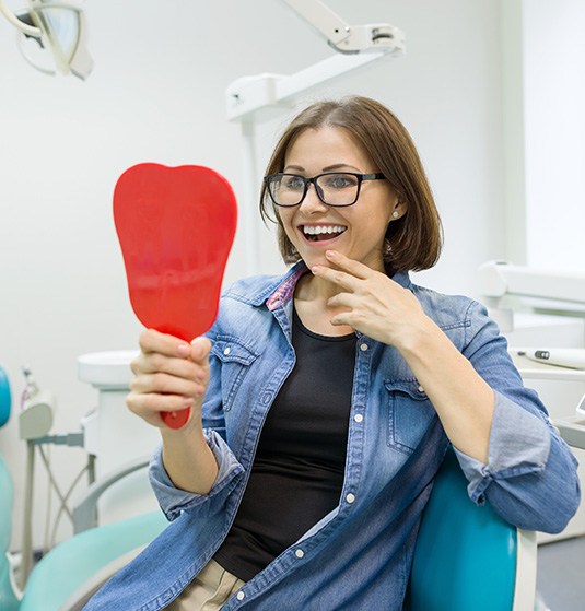 Patient looking at their smile in the mirror and appearing pleased
