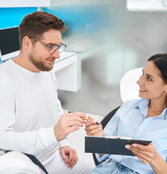 Dental staff discussing cost with female patient in treatment chair