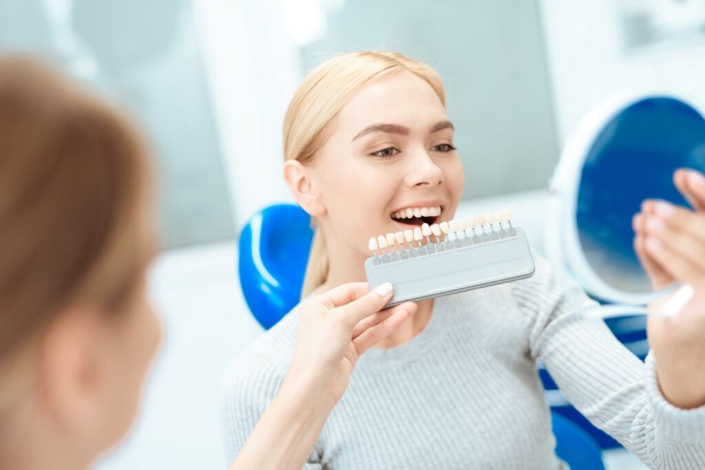 A woman looking in the mirror at her smile after cosmetic dentistry treatment