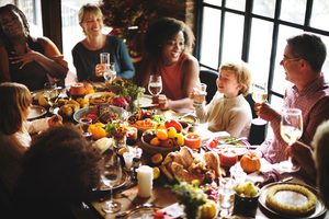 Group of people around a dinner table full of food and fall decorations